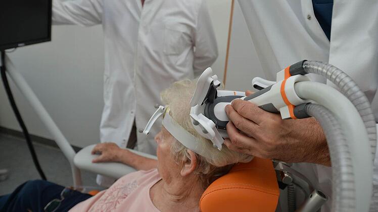 Die Magnetspule wird auf dem Kopf der Patientin platziert. Eine optische Zielerfassung mit einer Kamera wird in Gang gesetzt und überträgt das Innere des Schädels auf den Bildschirm. Foto: Ronald Rinklef
