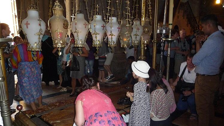Auf diese Platte soll Jesus gelegt worden sein, nachdem sein Leichnam vom Kreuz abgenommen wurde. Besucher der Grabeskirche in der Altstadt Jerusalems streichen ehrfürchtig mit ihren Smartphones oder Devotionalien über die Platte. Foto: irfe