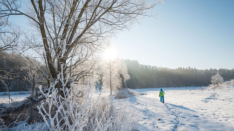 Ein Wanderer hinterlässt seine Fußspuren im Schnee der Vulkaneifel.