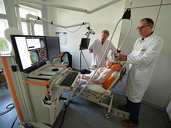 Hermann Weber (rechts) platziert die Spule zur Magnetstimulation auf dem Schädel der Patientin, während Peter Rieckmann die Navigation auf dem Bildschirm verfolgt. Foto: Ronald Rinklef