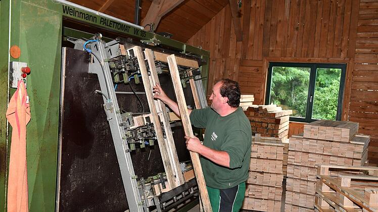Bretter und Klötze werden von Hand eingelegt, die Maschine (eine von vielen) nagelt dann alles zusammen: Günter Partheymüller bei der Fertigung von Paletten in Marktgraitz. Foto: Ronald Rinklef