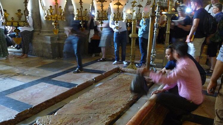 Auf diese Platte soll Jesus gelegt worden sein, nachdem sein Leichnam vom Kreuz abgenommen wurde. Besucher der Grabeskirche in der Altstadt Jerusalems streichen ehrfürchtig mit ihren Smartphones oder Devotionalien über die Platte, um ein bisschen von der "Heiligkeit" abzubekommen. Foto: irfe