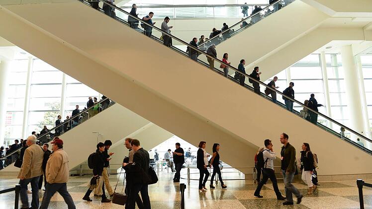 Teilnehmer kommen nach Tim Cooks Vortrag die Rolltreppen herunter. Foto: John G. Mabanglo/dpa
